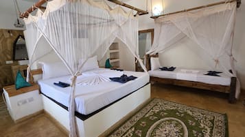 Ein Zimmer mit zwei Betten, jedes mit Baldachinvorhängen und Kissen. Auf dem Boden liegt ein grüner Teppich mit Muster.