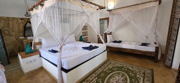 Una habitación con dos camas, cada una con dosel y almohadas. En el suelo, un tapete verde estampado.