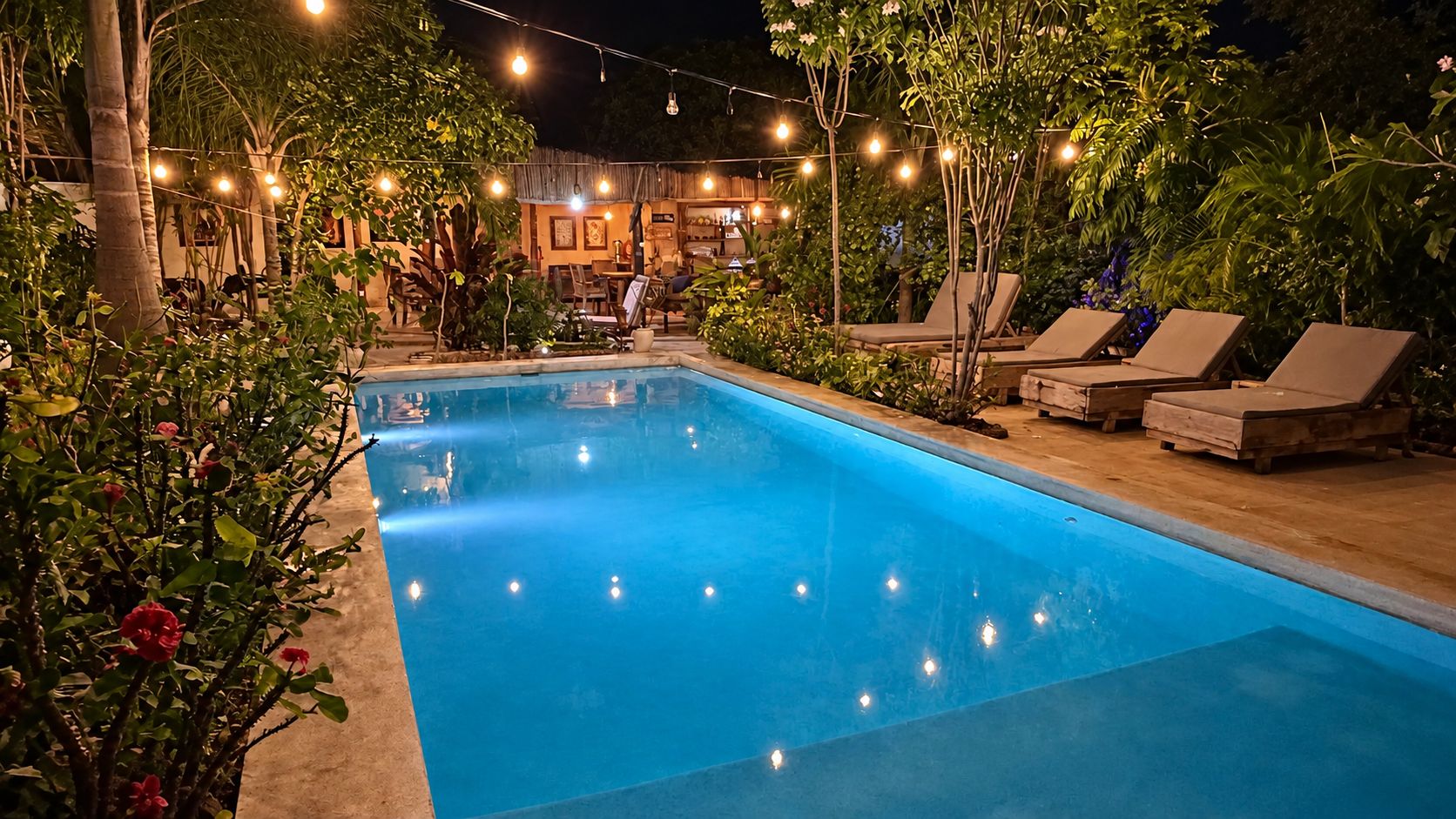 Una piscina con sillones de descanso e iluminación festiva.