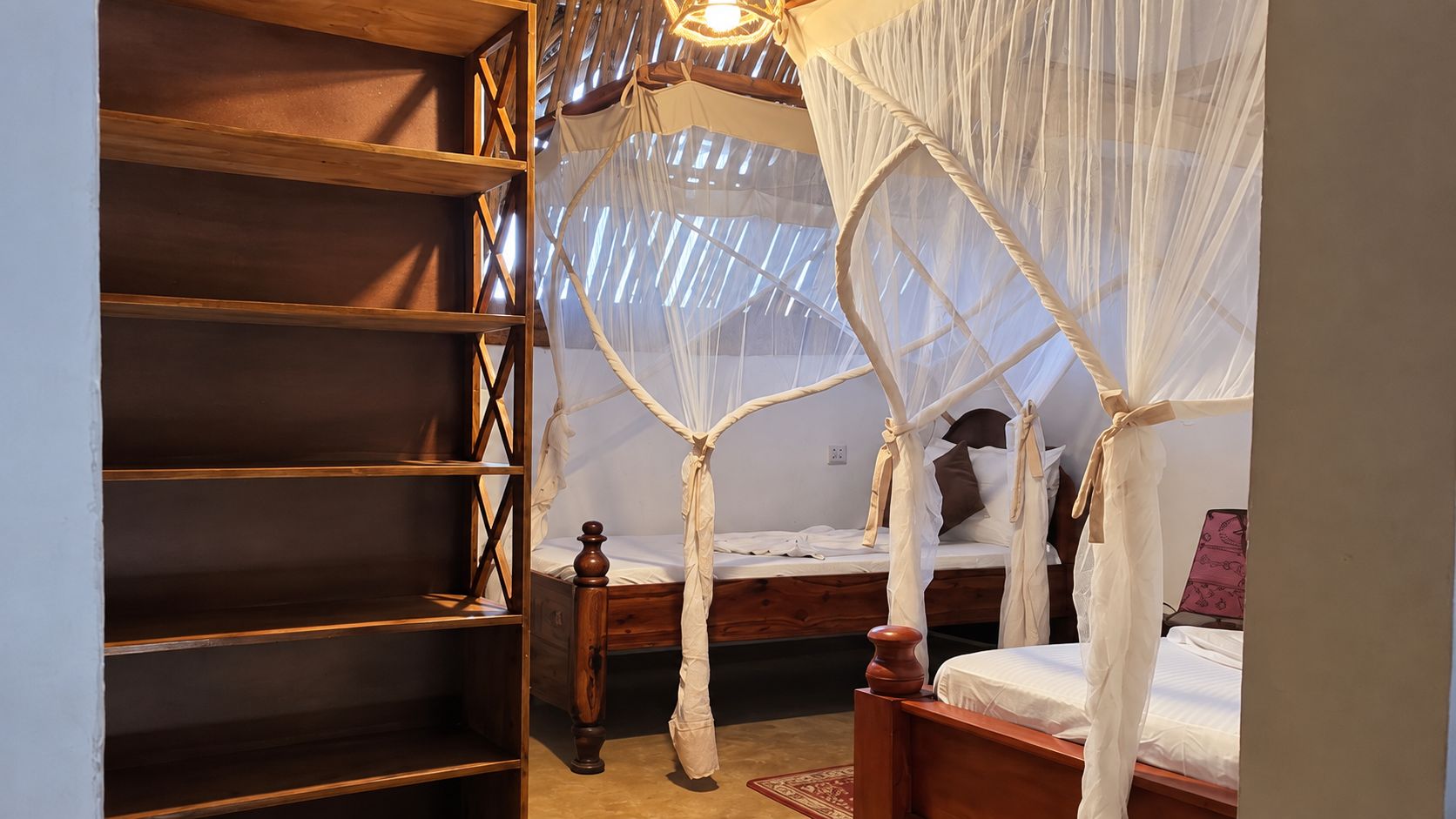 A bedroom with a canopy bed, a wooden bookshelf, and a small bedside table.