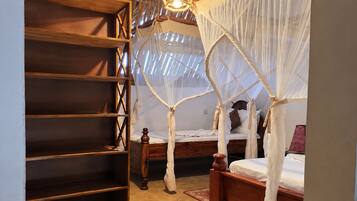 A bedroom with a canopy bed, a wooden bookshelf, and a small bedside table.
