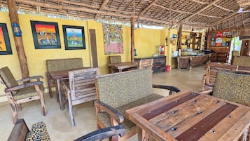 Un espacio de estar al aire libre rústico con mobiliario de madera y techo de paja.