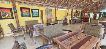 Un espacio de estar al aire libre rústico con mobiliario de madera y techo de paja.