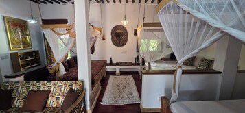 Una habitación con una cama, un banco, un estante en la pared y un adorno colgante.