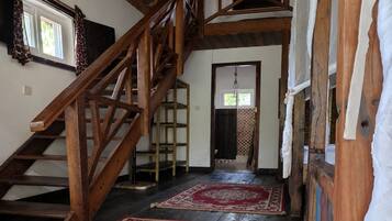 A wooden staircase leading to a landing with a red patterned rug.