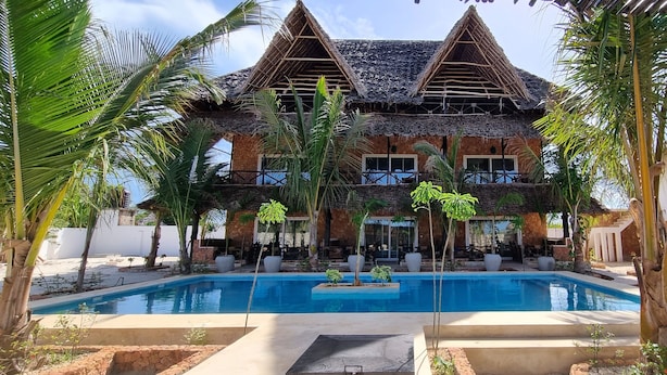 A resort with a pool, thatched-roof buildings, and tropical landscaping. - Salama & Mbuyuni Bungalows (Matemwe)