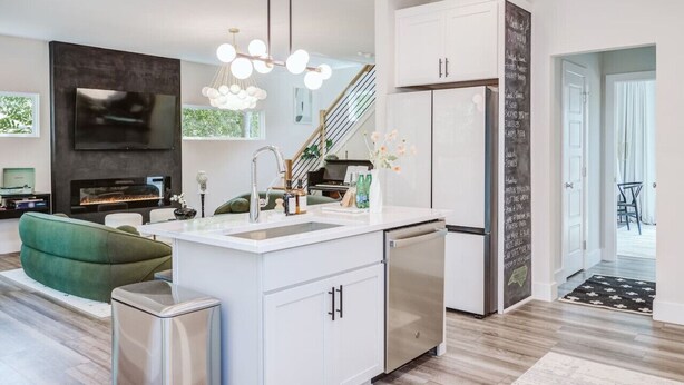 Una cocina moderna con muebles blancos, un refrigerador de acero inoxidable y un lavavajillas empotrado.