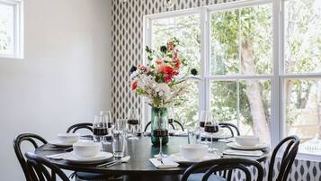 A dining table set for six with a vase of flowers in the center, surrounded by chairs.
