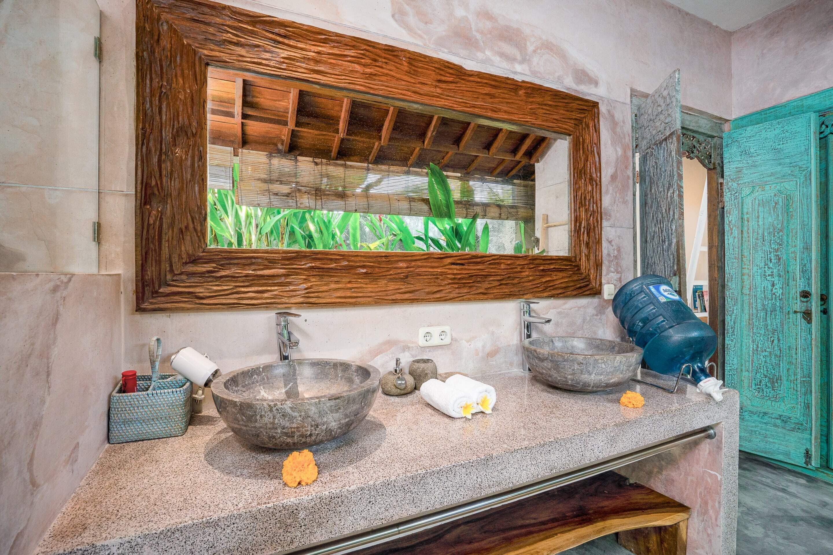 A bathroom with a large mirror, two bowls, a towel, and a water dispenser.