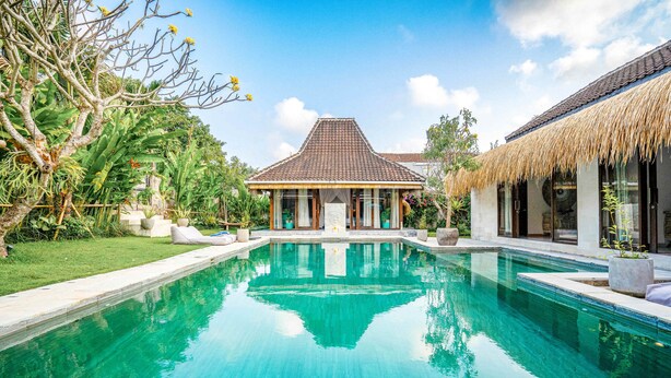 Una piscina con una casa al fondo.
