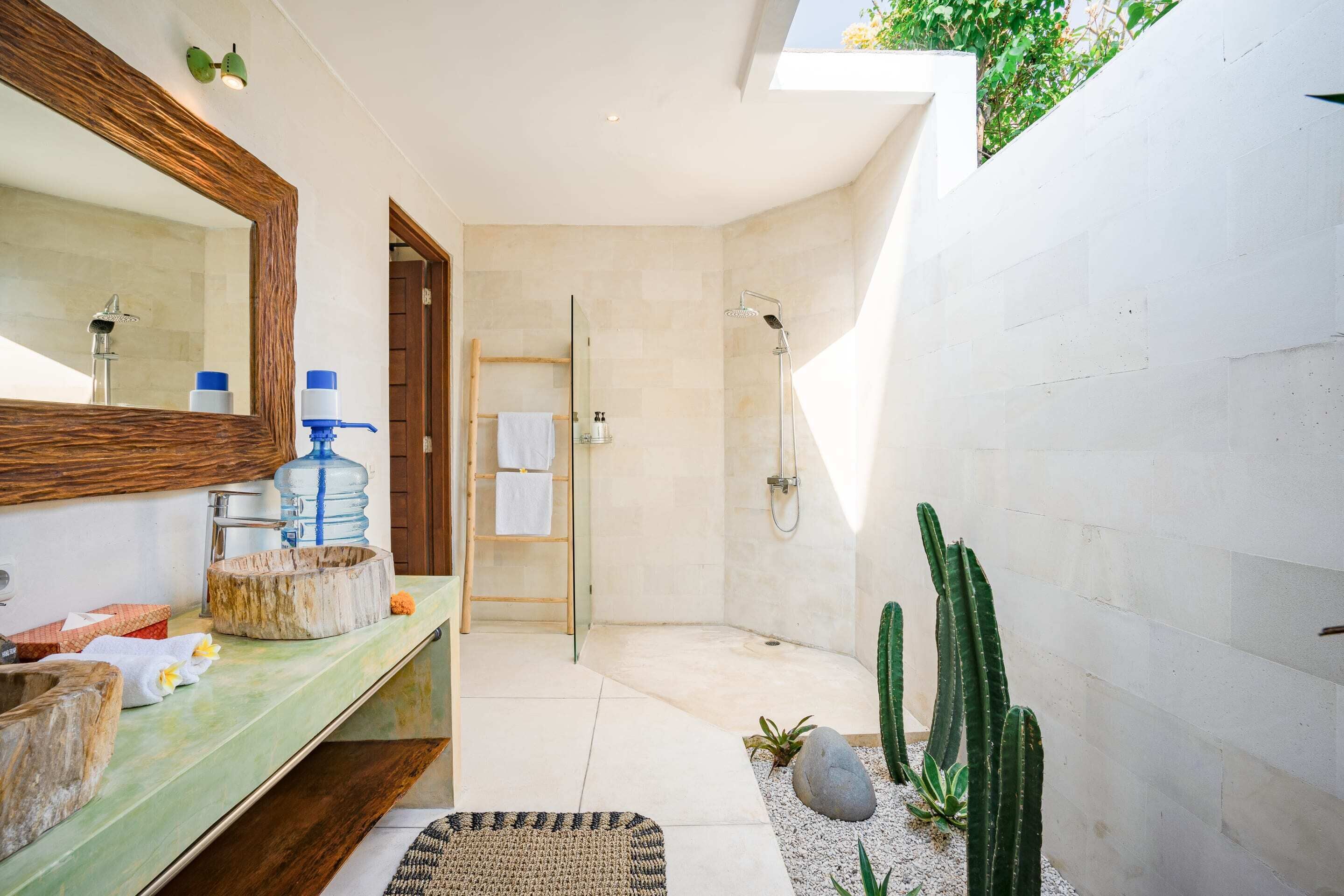 A modern bathroom with a large mirror, a shower, and a sink with a water dispenser.