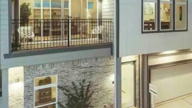 Un immeuble de deux étages doté d’un balcon, d’un garage et d’une façade en pierre.