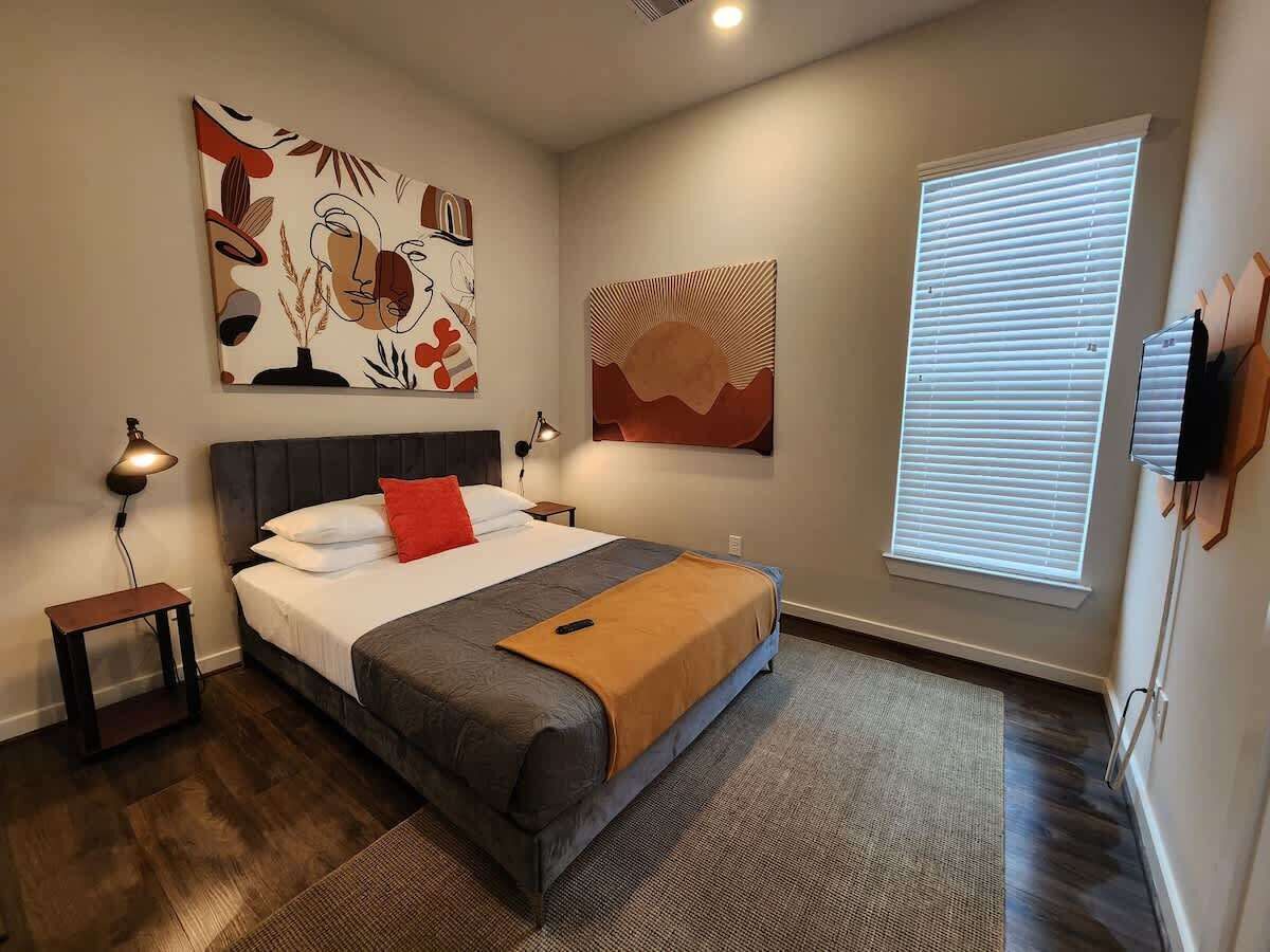 Een moderne hotelkamer met een groot bed, een nachtkastje, een lamp en kunstwerken aan de wanden.