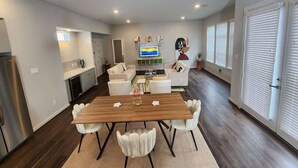 Un salon moderne avec une table à manger en bois, des canapés blancs et un téléviseur.