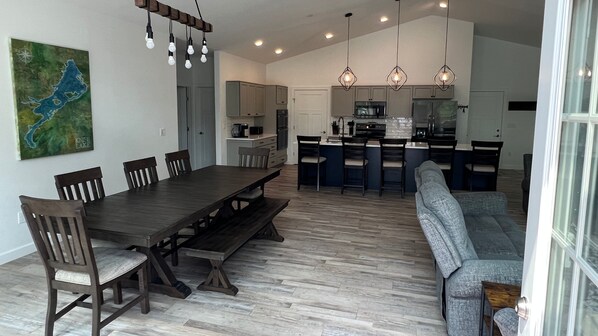 A modern kitchen with a central island, wooden dining table, and built-in seating.