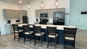 Una cocina moderna con una isla central, taburetes de bar e iluminación colgante.