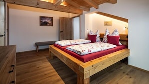 Un letto di legno con biancheria rossa in una stanza con pavimento di legno e soffitto spiovente.