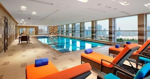 Relax by the pool with expansive city views and comfortable seating options.
