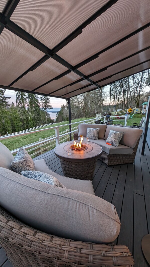 An outdoor deck with a fire pit, wicker furniture, and a view of the surrounding landscape.