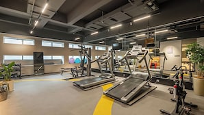 Ein Fitnessstudio mit Laufbändern, Kraftgeräten und einer Spiegelwand.