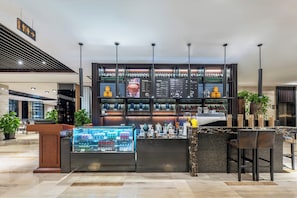 A modern bar area with a counter, seating, and a display case.