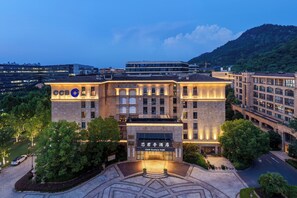 Un hotel con una entrada destacada, varios pisos y un patio ajardinado.