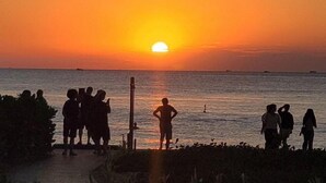 A sunset over the ocean with silhouettes of people on a beach. - E3 Homestay & Cafe Phu Quoc (Phu Quoc)