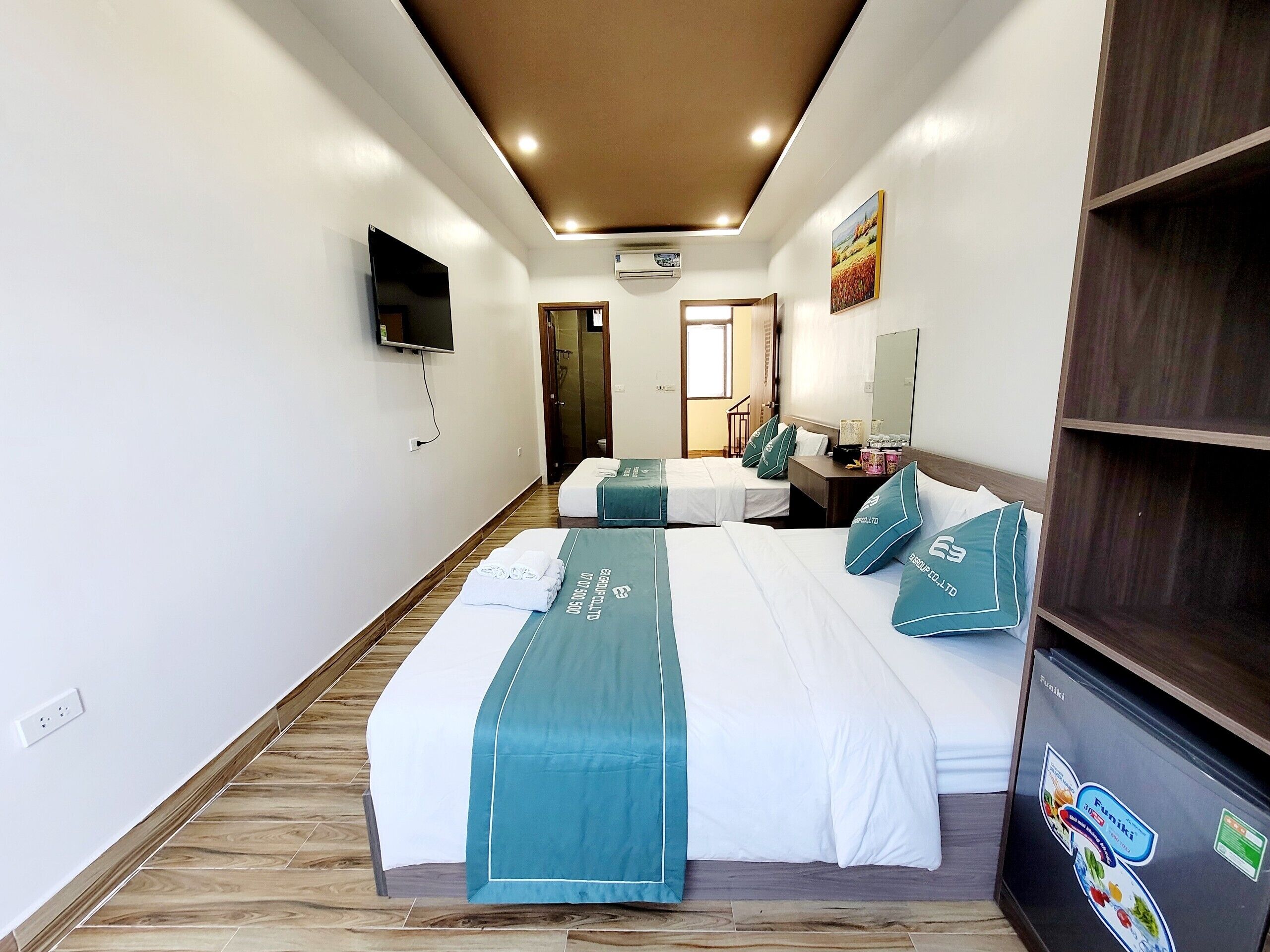 A hotel room with two beds, a TV, a desk, and a wardrobe.