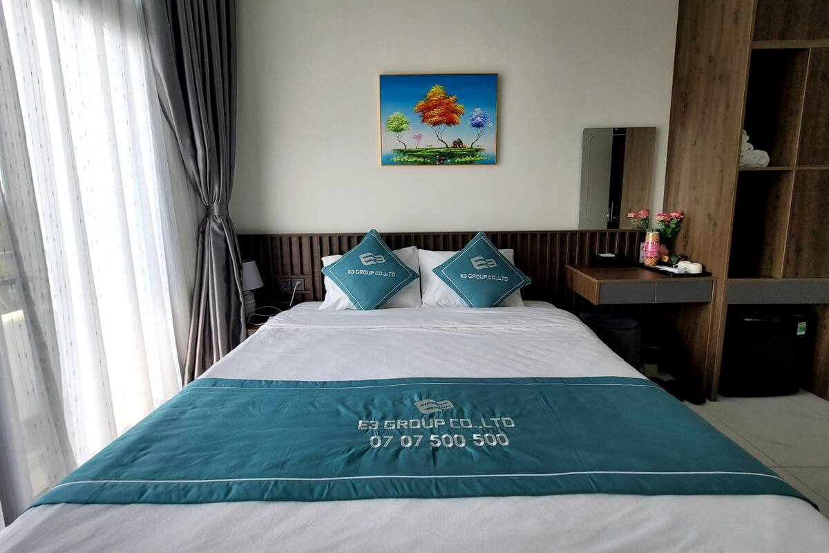 Une chambre d’hôtel avec un lit, un tableau, un bureau et un miroir.