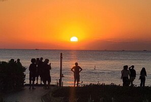 A sunset over the ocean with silhouettes of people on a beach. - E3 Homestay & Cafe Phu Quoc (Phu Quoc)