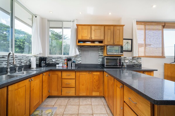 A modern kitchen with wooden cabinets, a black countertop, and a microwave. - Villa Elysian Beachfront Luna Studio Sleeps 4 (Provincia de Guanacaste)