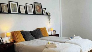 A bedroom with two beds, wooden flooring, and a hanging light fixture. - Lisbon - Low Cost - Airport - Subway (Lisboa)