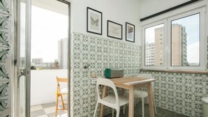 A small room with a window, a table, and a chair. There are framed pictures on the wall. - Lisbon - Low Cost - Airport - Subway (Lisboa)