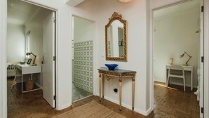 A hallway with a white door, a small table with a blue bowl, and a gold-framed mirror on the wall. - Lisbon - Low Cost - Airport - Subway (Lisboa)