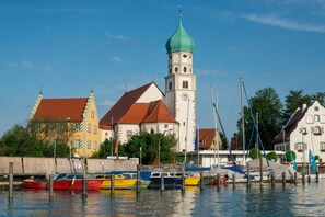 Ein Ufer mit vertäuten Booten, eine Kirche mit grüner Kuppel und traditionelle Gebäude.