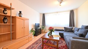 A living room with a sofa, a TV, a cabinet, and a red patterned rug. - Apartment "Haus Kaulitzki" with Lake View, Private Terrace & Wi-Fi (Wasserburg (Bodensee))