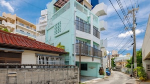 Un edificio residencial de varios pisos con balcones, un garaje y vista a la calle.