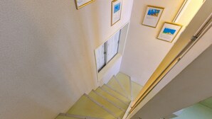 Una escalera con barandilla, una ventana y cuadros en la pared.