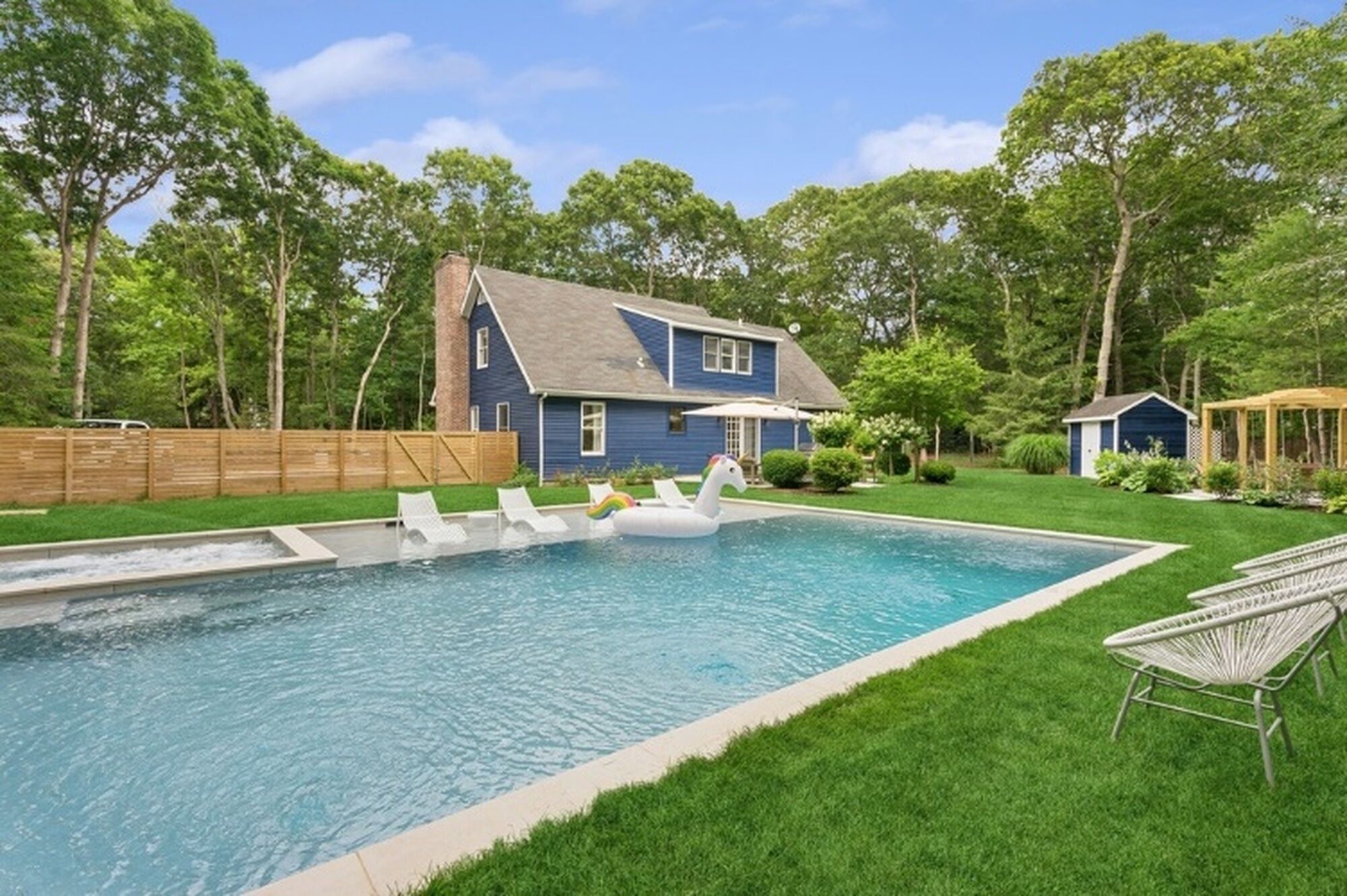 Ein Garten mit Swimmingpool, einem Haus und einer Holzterrasse.