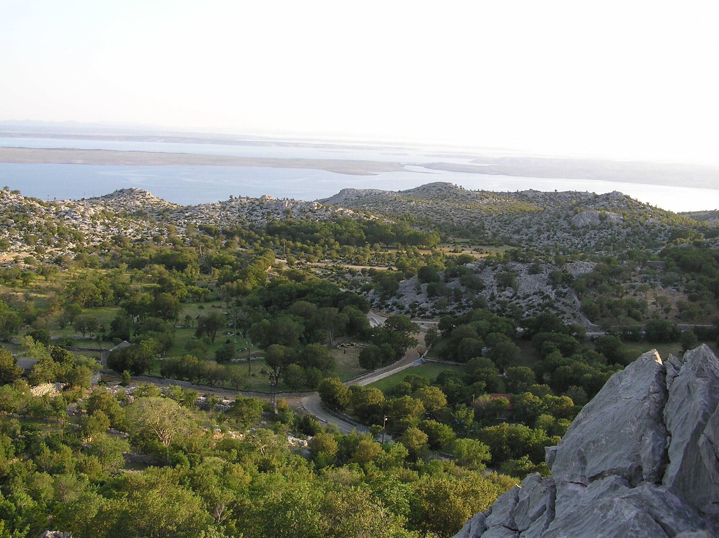 Un paysage montagneux avec une route sinueuse, une végétation luxuriante et un terrain rocheux.