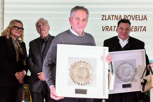 A group of people holding framed artworks at an event.
