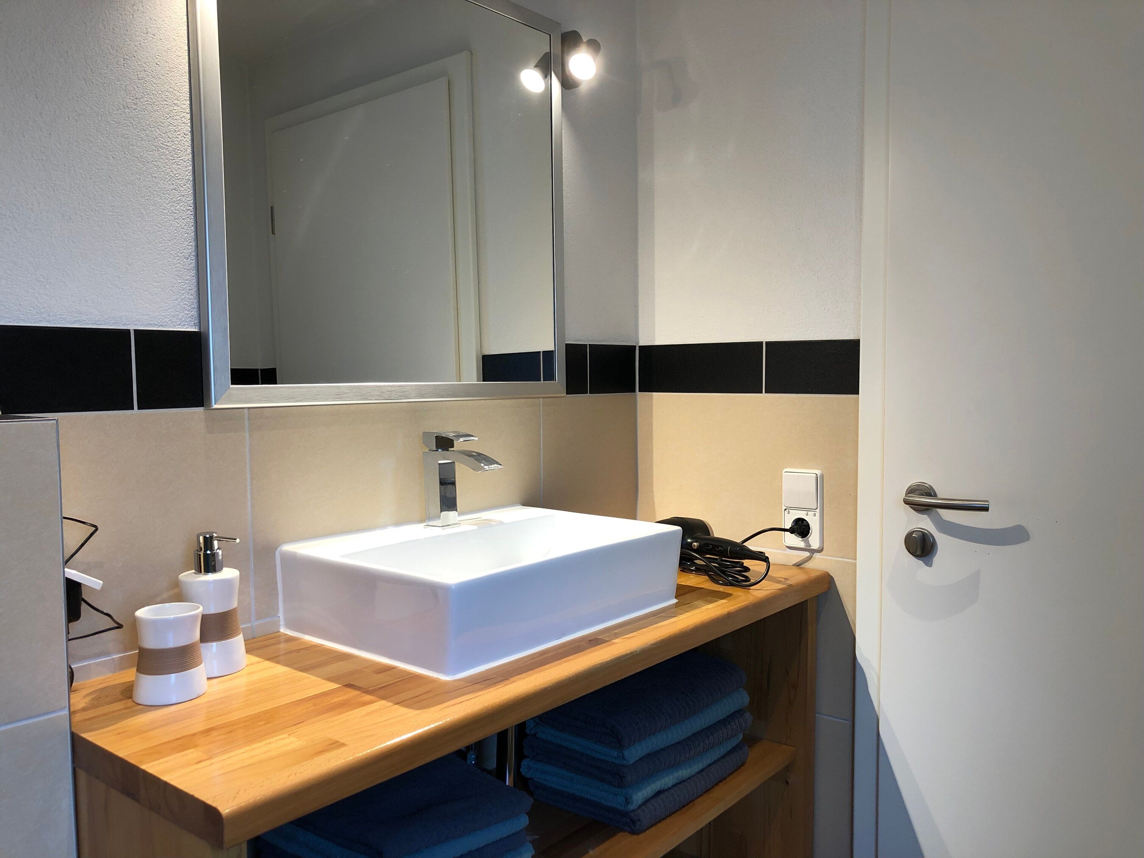 A bathroom with a white sink, a mirror, a towel rack, and a door.