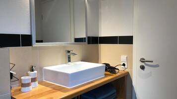 A bathroom with a white sink, a mirror, a towel rack, and a door.