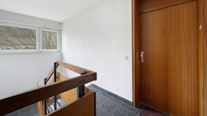 Un escalier avec des rampes en bois, une porte en bois et une fenêtre donnant sur des arbres.