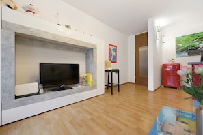 Ein Wohnzimmer mit Fernseher, Kamin, einem roten Kühlschrank und Holzboden.