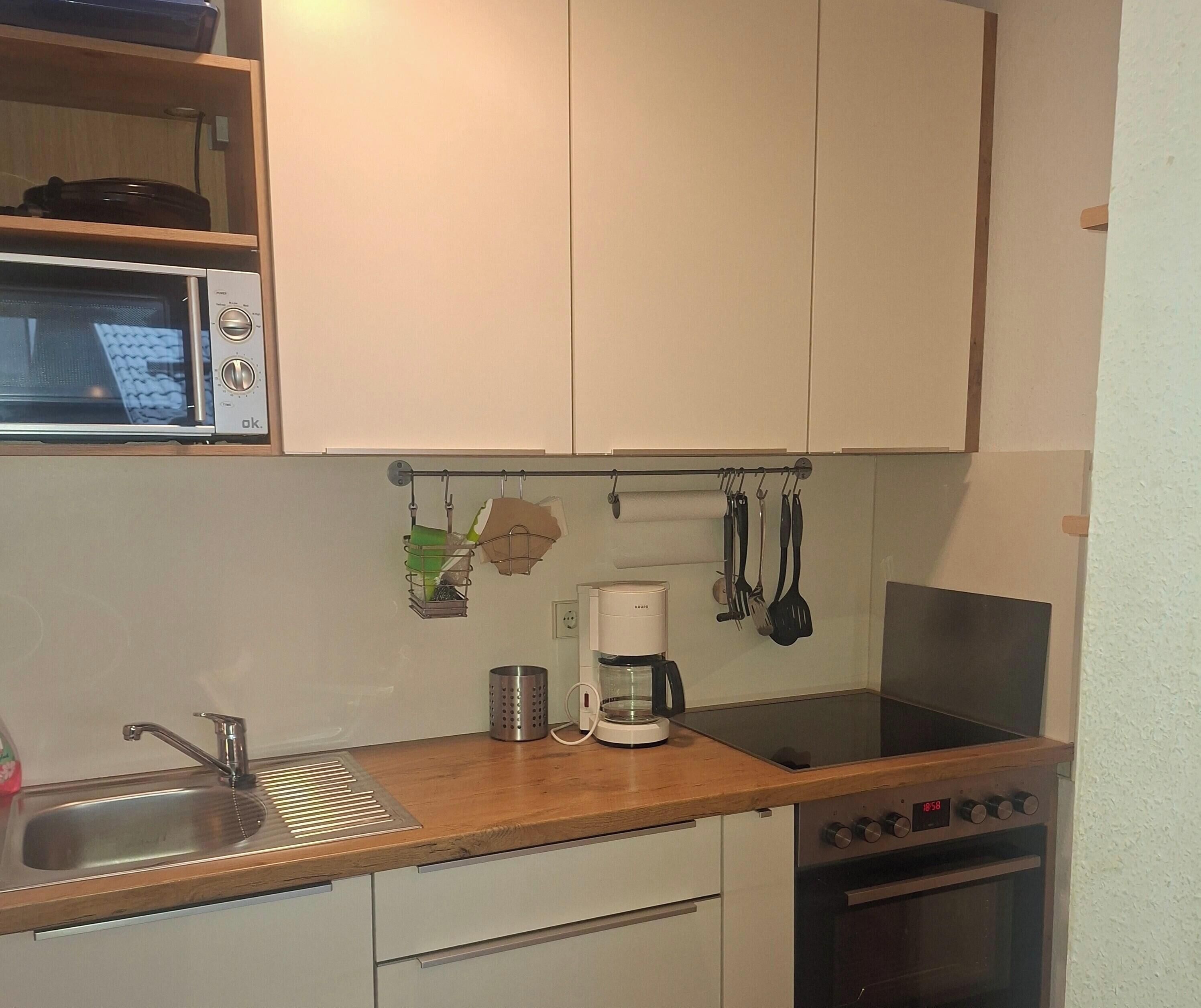 Una cocina compacta equipada con microondas, cafetera y estufa.