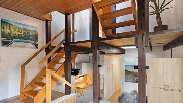 Un intérieur moderne avec un escalier en bois, un coin cuisine et un espace repas.