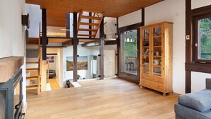 Un intérieur moderne avec un escalier en bois, un meuble avec des portes en verre et une vue dégagée sur l’extérieur grâce à une grande fenêtre.