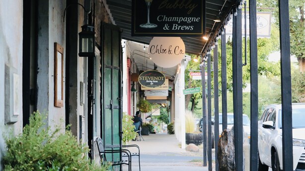 Eine Straße mit Außenplätzen, ein Café namens 'Chloe & Co.' und ein Schild für 'The Pubby Champagne & Brews'.