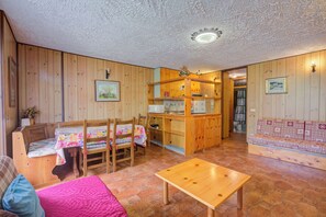 A cozy interior with a wooden dining area, a sofa, and a small table.